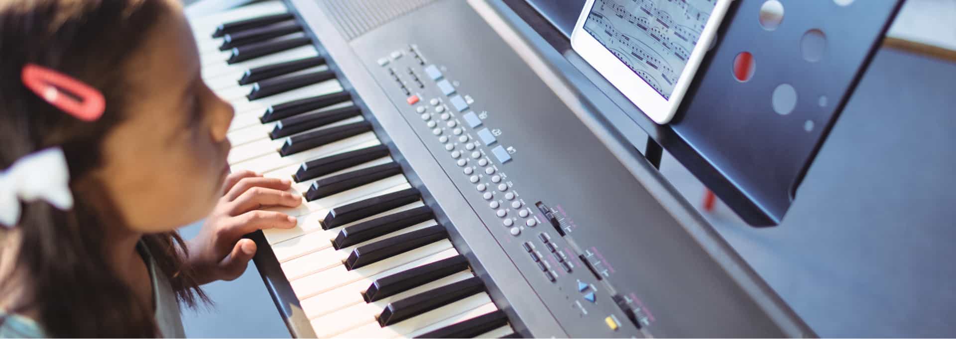 Young girl with brown hair playing piano for 88 keys music academy child lessons near me